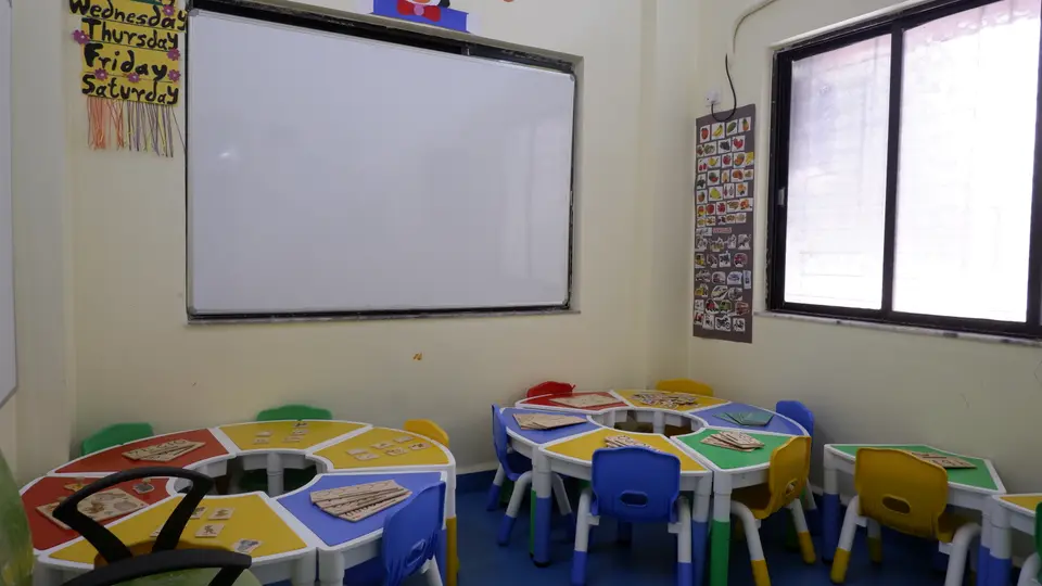 Classroom with whiteboard and group tables set with letter-tracing boards